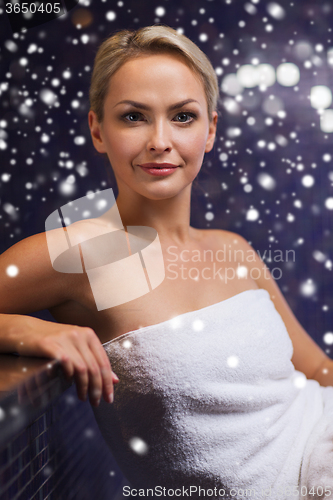 Image of beautiful woman sitting in bath towel at sauna