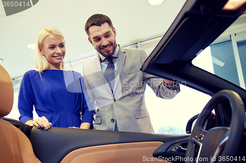 Image of happy couple buying car in auto show or salon