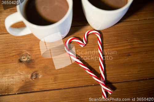 Image of christmas candy canes and cups on wooden table