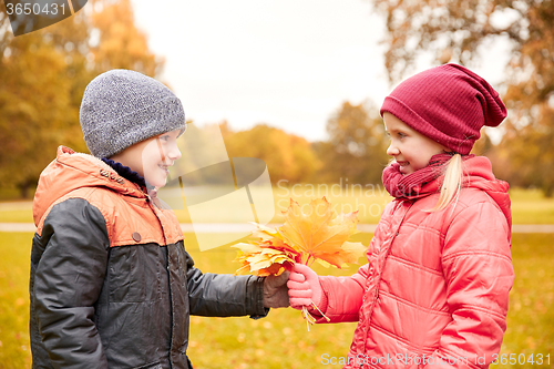 Image of little boy giving autumn maple leaves to girl