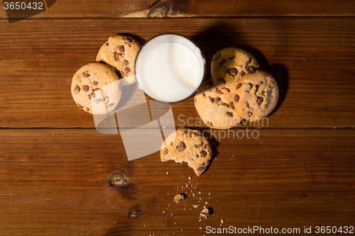 Image of close up of oat cookies and milk on wooden table