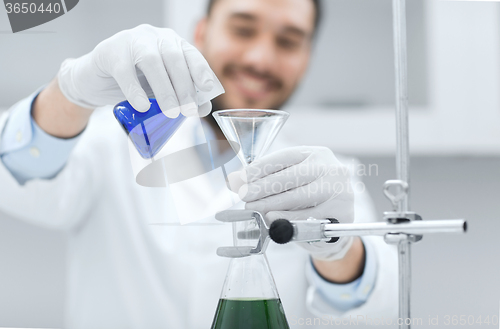 Image of close up of scientist with test tubes and funnel