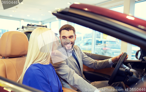 Image of happy couple buying car in auto show or salon