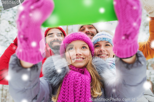 Image of smiling friends with tablet pc in winter forest