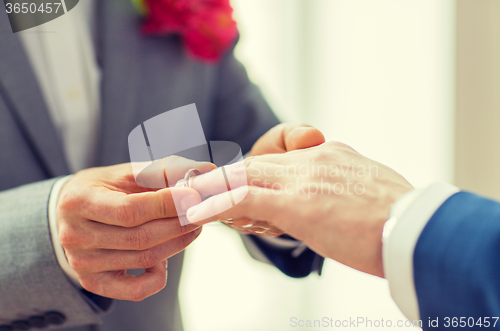 Image of close up of male gay couple hands and wedding ring