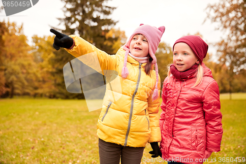 Image of happy little girls pointing finger in autumn park