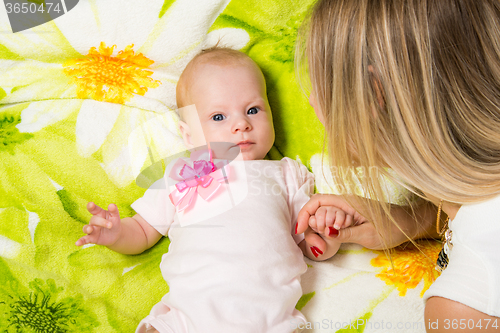 Image of The two-month baby lying on the bed, sitting next to mom