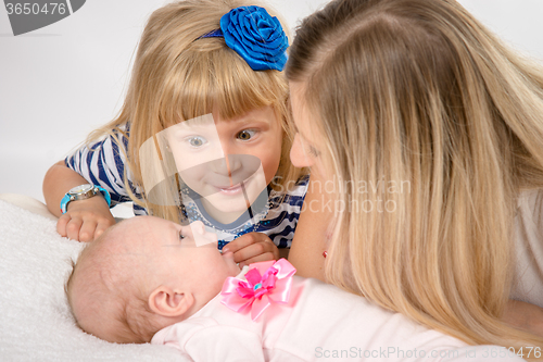 Image of Five-year girl with amazement looks at his newborn sister