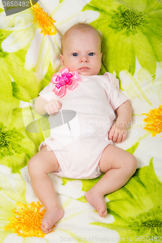 Image of The two-month baby lying on the bed on his back looking at the frame