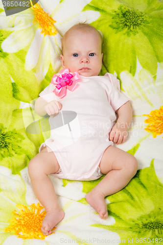 Image of The two-month baby lying on the bed on his back looking at the frame