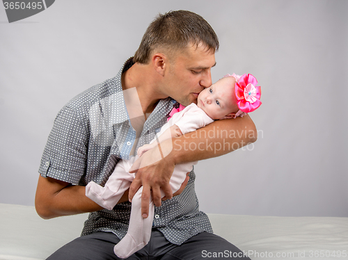 Image of Happy dad kisses his infant daughter two months