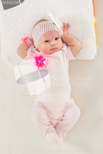 Image of Baby girl lying in bed stretching