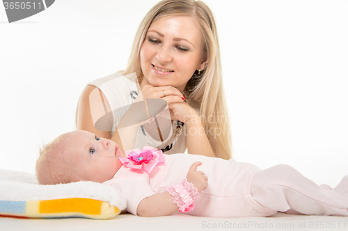 Image of Mom looks at lying on the bed his two-year daughter