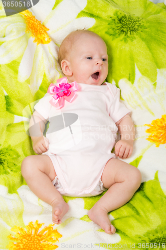 Image of The two-month baby yawns lying on his back on the bed