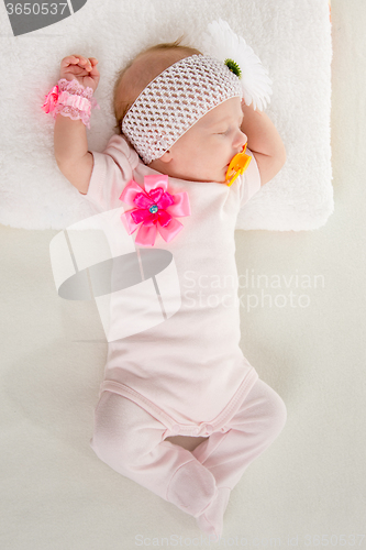 Image of The two-month girl sleeps on the bed at the head outstretched hands