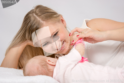 Image of Mom is near a two-month baby and lovingly looks at him