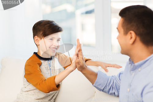 Image of happy father and son doing high five at home