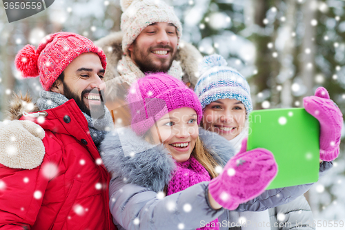 Image of smiling friends with tablet pc in winter forest