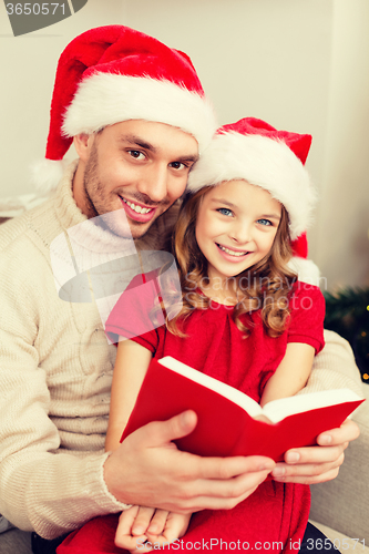 Image of smiling father and daughter reading book