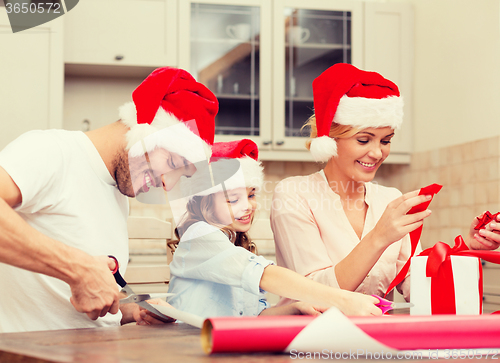 Image of smiling family in santa helper hats with gift box