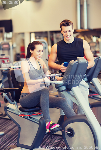 Image of happy woman with trainer on exercise bike in gym