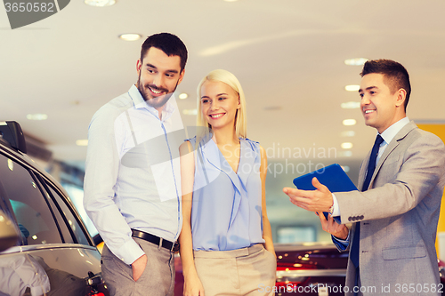Image of happy couple with car dealer in auto show or salon