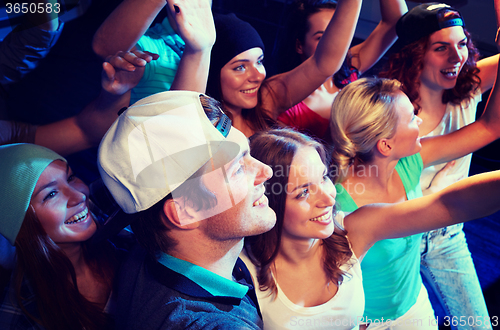 Image of smiling friends at concert in club