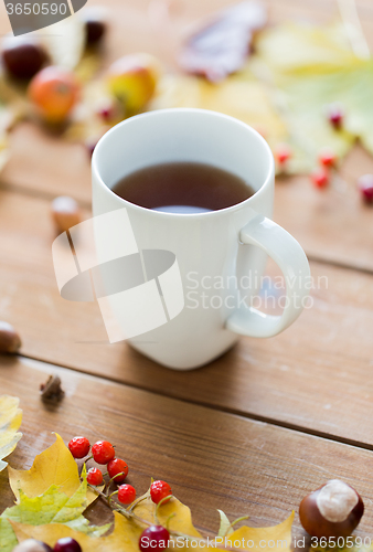 Image of close up of tea cup on table with autumn leaves