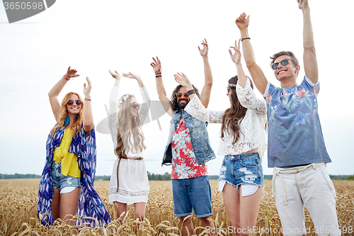 Image of happy young hippie friends dancing outdoors