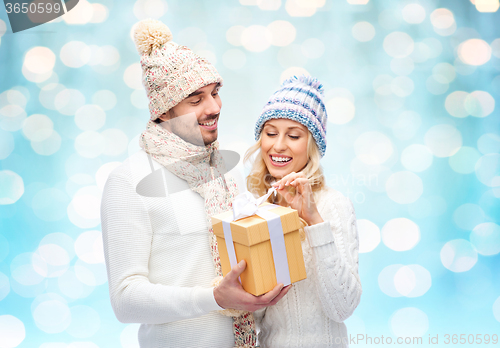 Image of smiling couple in winter clothes with gift box