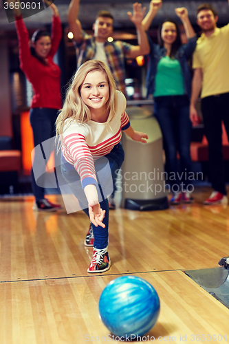 Image of happy young woman throwing ball in bowling club