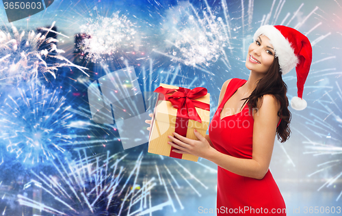 Image of happy woman in santa hat with gift over firework