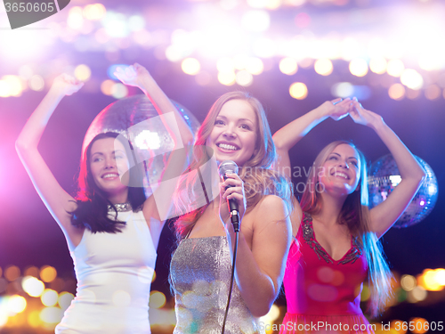 Image of happy women singing karaoke and dancing