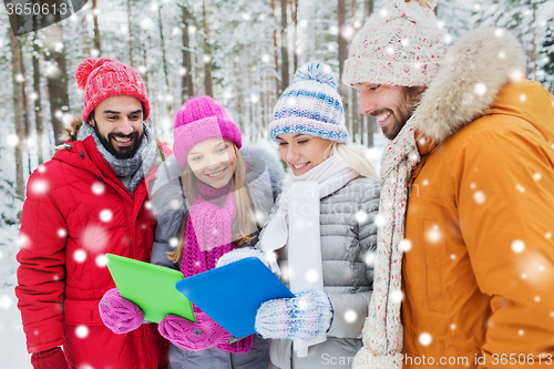 Image of smiling friends with tablet pc in winter forest
