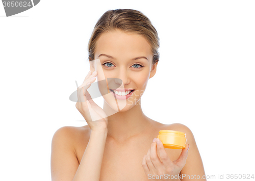 Image of happy young woman appying cream to her face