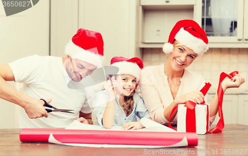 Image of smiling family in santa helper hats with gift box