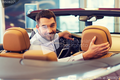 Image of happy man sitting in car at auto show or salon