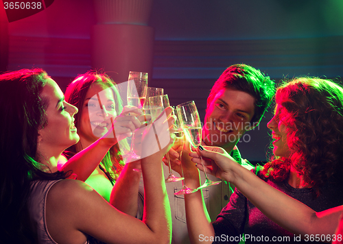 Image of smiling friends with glasses of champagne in club