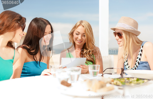 Image of smiling girls looking at tablet pc in cafe
