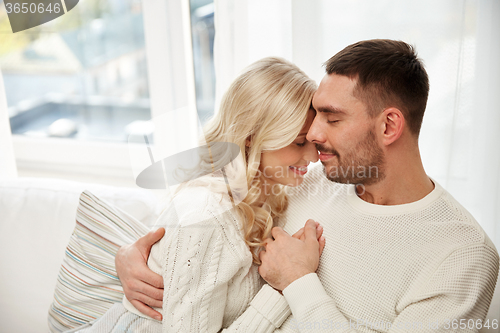 Image of happy couple covered with plaid on sofa at home