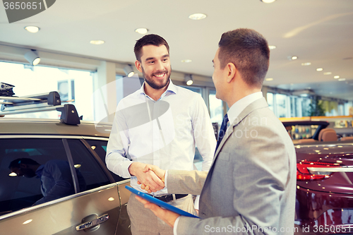 Image of happy man shaking hands in auto show or salon