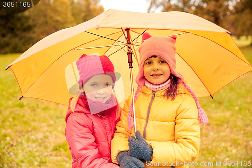 Image of happy little girls with umbrella in autumn park