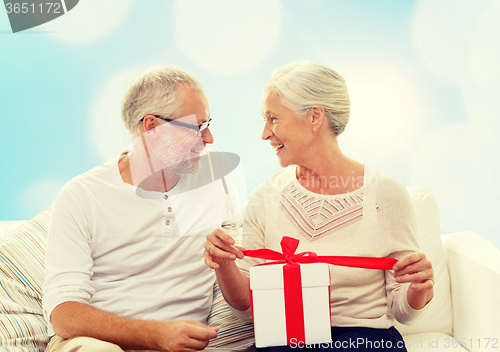 Image of happy senior couple with gift box at home