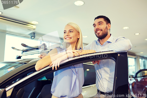 Image of happy couple buying car in auto show or salon