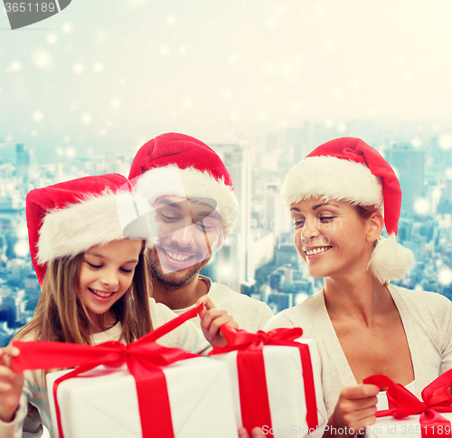 Image of happy family in santa helper hats with gift boxes