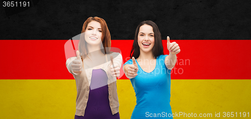 Image of smiling girls showing thumbs up over german flag