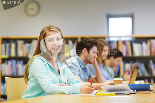 Image of happy student girl writing to notebook in library