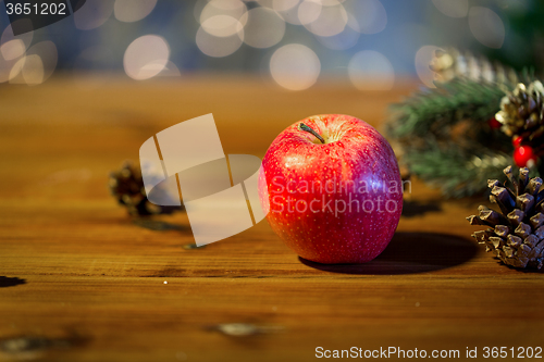 Image of close up of apple with fir decoration on wood