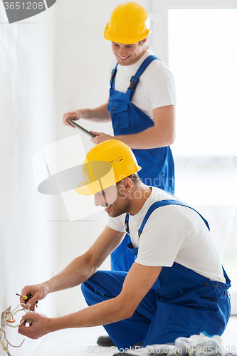 Image of builders with tablet pc and fixing wiring indoors