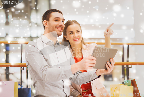 Image of couple with tablet pc and shopping bags in mall